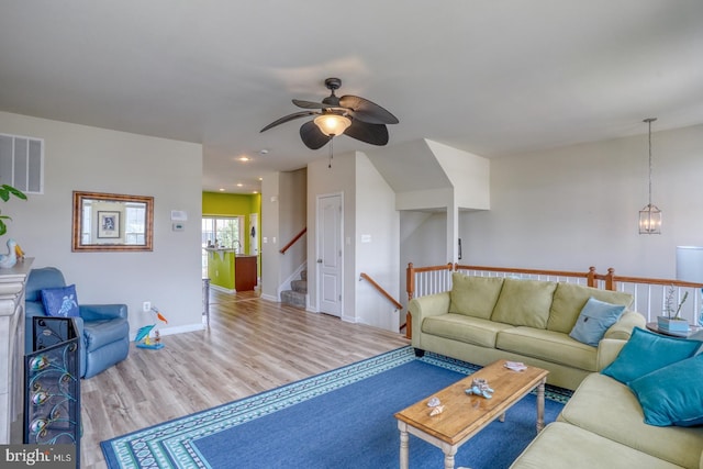 living room with a ceiling fan, baseboards, visible vents, and wood finished floors