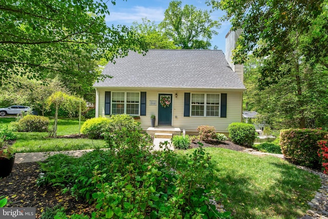 view of front of home with a chimney, a shingled roof, and a front lawn