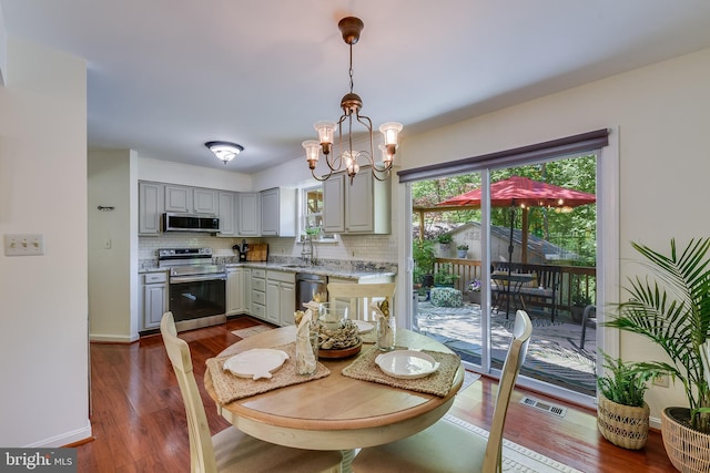 dining space with visible vents, dark wood-style flooring, baseboards, and an inviting chandelier