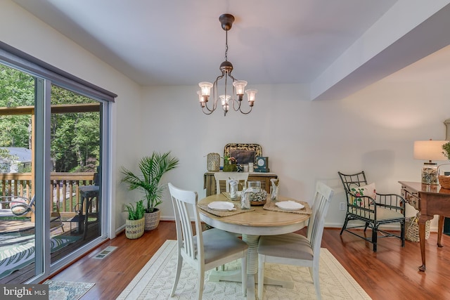 dining space featuring visible vents, baseboards, wood finished floors, and a notable chandelier