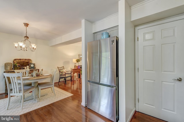 dining space featuring an inviting chandelier, ornamental molding, and dark wood-type flooring