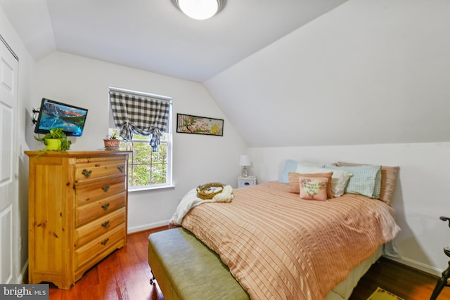 bedroom with baseboards, wood finished floors, and lofted ceiling