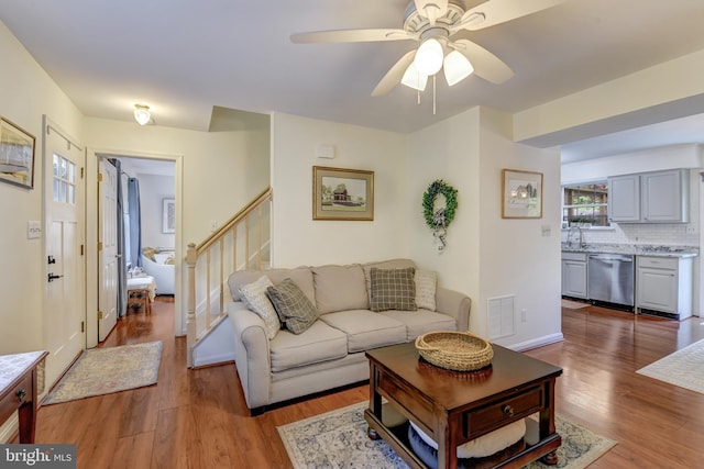 living area with a ceiling fan, stairs, wood finished floors, and visible vents