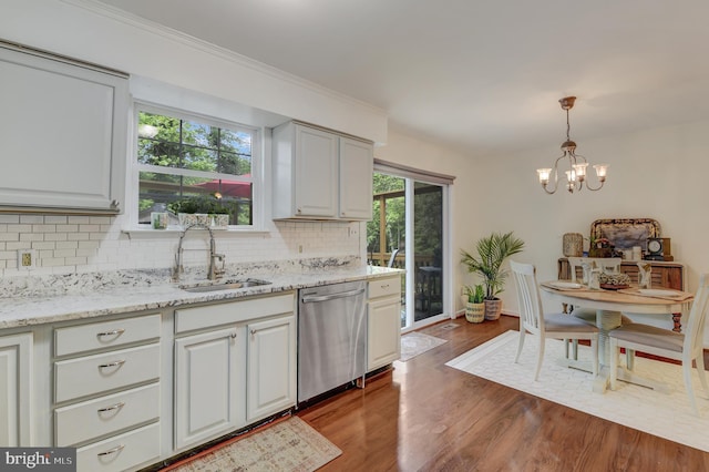 kitchen featuring tasteful backsplash, a sink, dark wood finished floors, dishwasher, and a notable chandelier