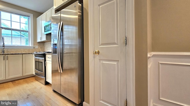 11441 Log Ridge Dr, Fairfax, VA 22030 - kitchen with stainless steel appliances, light wood-type flooring, dark stone counters, white cabinets, and a sink