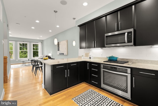 631 Regent Pl NE, Washington, DC 20017 - kitchen featuring appliances with stainless steel finishes, dark cabinetry, a peninsula, light wood-style flooring, and recessed lighting
