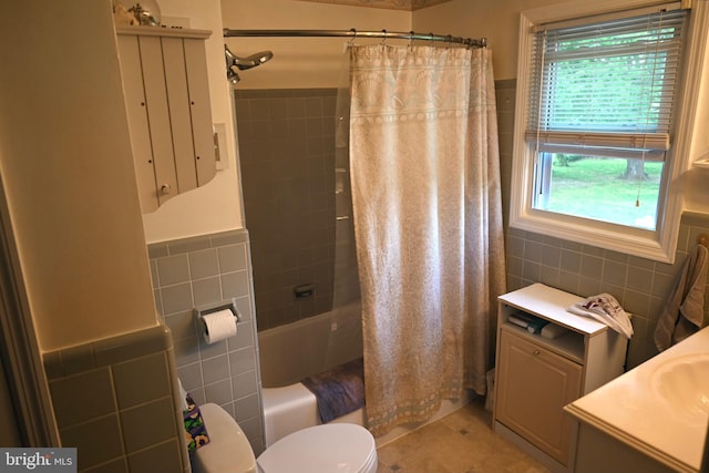 bathroom with tile walls, healthy amount of natural light, shower / bath combo, toilet, and a wainscoted wall