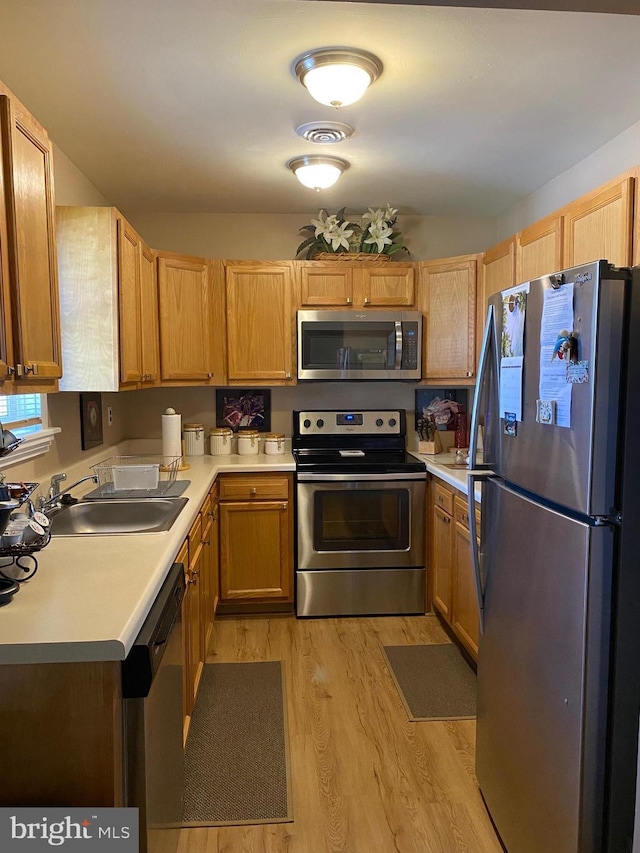 kitchen with visible vents, appliances with stainless steel finishes, light wood-type flooring, a sink, and light countertops