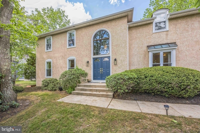 view of front of house with stucco siding and a front yard