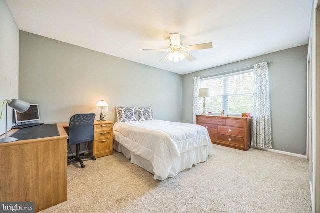 bedroom featuring light colored carpet, a desk, baseboards, and a ceiling fan