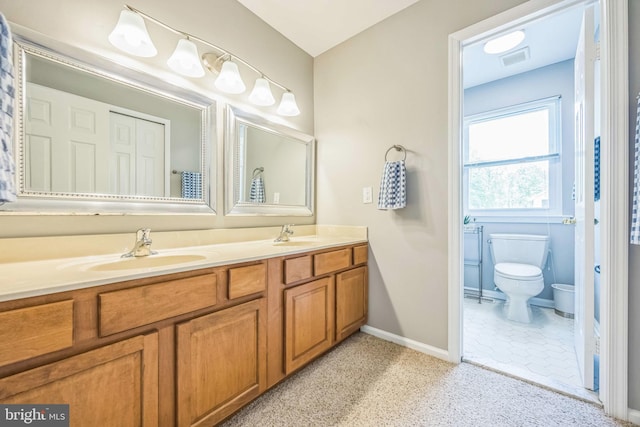 bathroom with double vanity, baseboards, and toilet