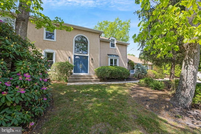 view of front facade with stucco siding and a front lawn