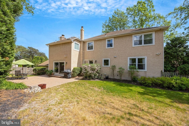 rear view of house featuring a patio area, stucco siding, and a chimney