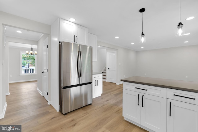kitchen featuring freestanding refrigerator, dark countertops, light wood finished floors, and white cabinets