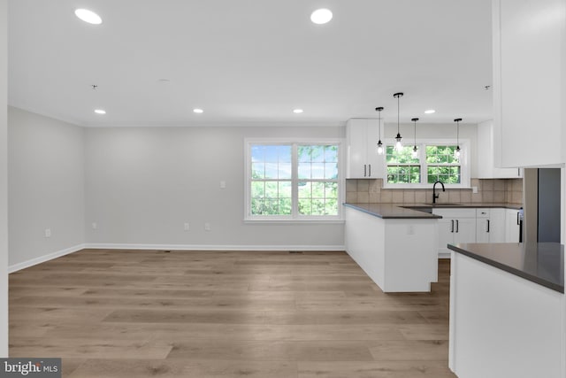 kitchen with a sink, white cabinetry, dark countertops, and recessed lighting