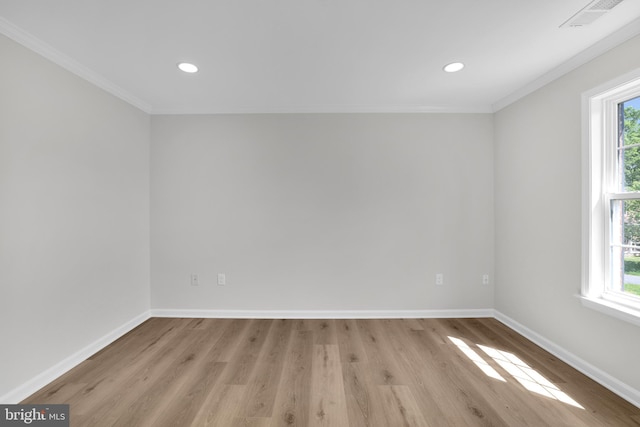 empty room with crown molding, a wealth of natural light, visible vents, and wood finished floors