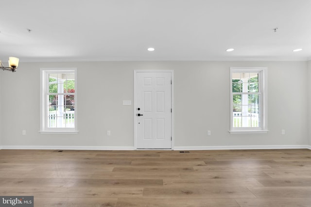 interior space with crown molding, baseboards, light wood-style flooring, and an inviting chandelier