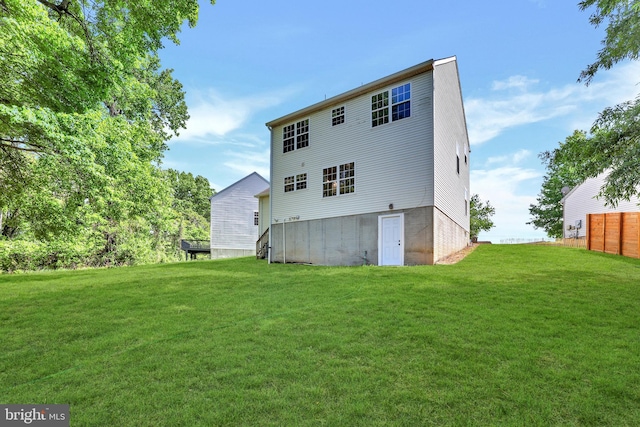 rear view of property featuring a yard and fence