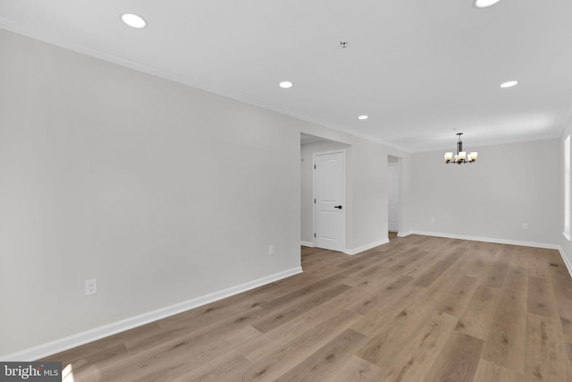 empty room featuring light wood-type flooring, baseboards, recessed lighting, crown molding, and a notable chandelier