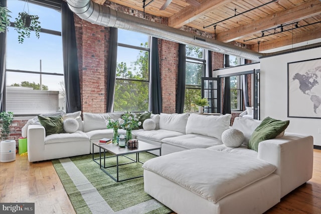 living room featuring wooden ceiling, wood-type flooring, beamed ceiling, and brick wall