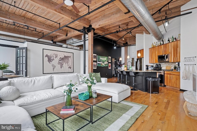 living area featuring beam ceiling, track lighting, wooden ceiling, ceiling fan, and light wood-style floors