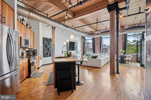 kitchen featuring light wood-style flooring, a breakfast bar area, modern cabinets, open floor plan, and appliances with stainless steel finishes