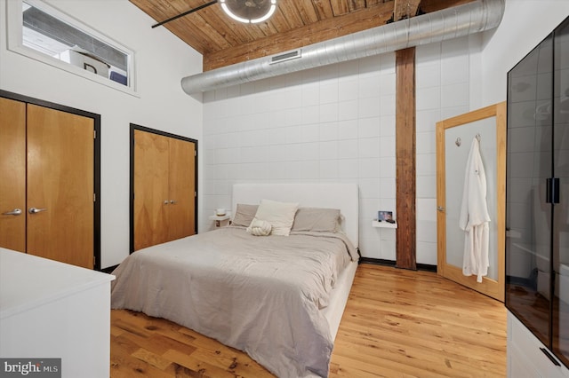 bedroom featuring wooden ceiling, visible vents, light wood-style flooring, and multiple closets