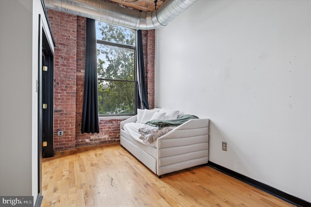 living area featuring light wood finished floors and brick wall