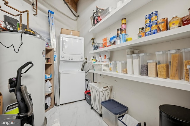 laundry room featuring marble finish floor, laundry area, and stacked washer / dryer