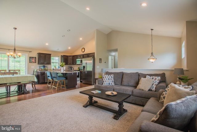 living room with an inviting chandelier, dark wood-style flooring, dark carpet, high vaulted ceiling, and recessed lighting