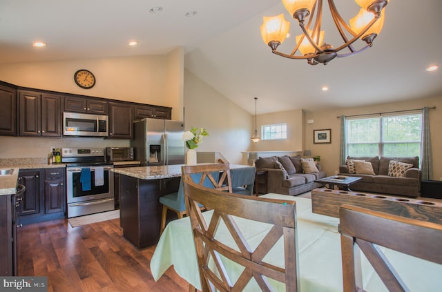 kitchen with dark brown cabinetry, light stone countertops, open floor plan, a chandelier, and stainless steel appliances