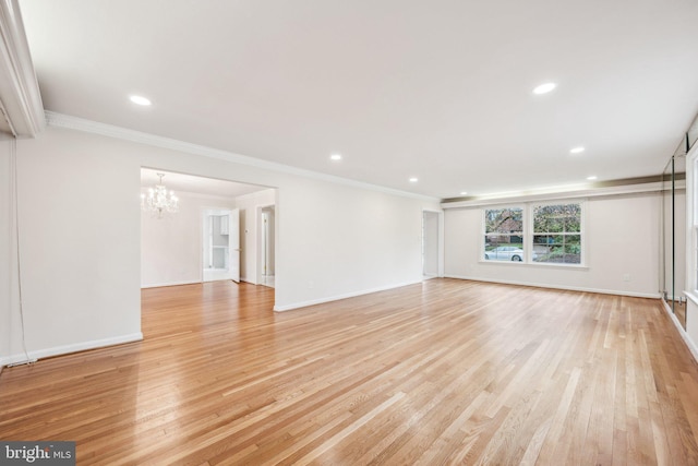 unfurnished living room featuring crown molding, recessed lighting, light wood-style flooring, and a notable chandelier