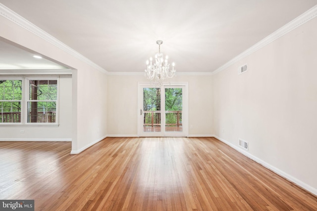 unfurnished room featuring plenty of natural light, light wood-style flooring, a chandelier, and visible vents