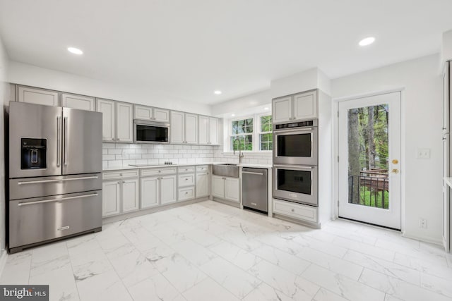 kitchen with light countertops, a sink, marble finish floor, and stainless steel appliances