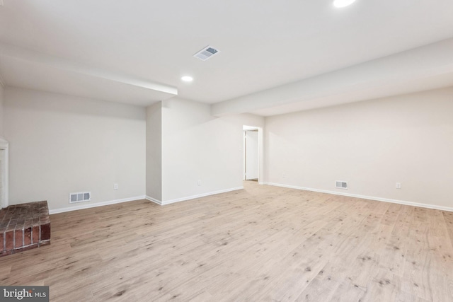 below grade area with baseboards, wood finished floors, and visible vents