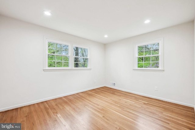 unfurnished room featuring a healthy amount of sunlight, baseboards, and light wood finished floors