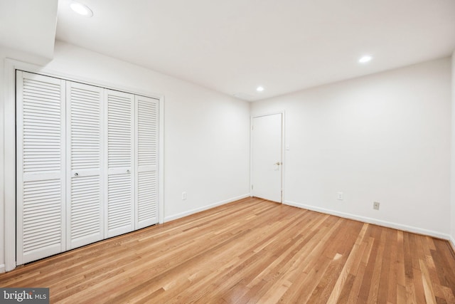 unfurnished bedroom featuring baseboards, a closet, recessed lighting, and wood finished floors