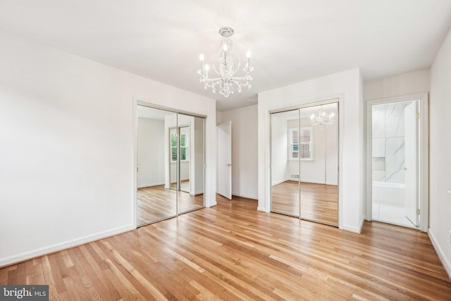 unfurnished bedroom with baseboards, two closets, light wood finished floors, and a notable chandelier