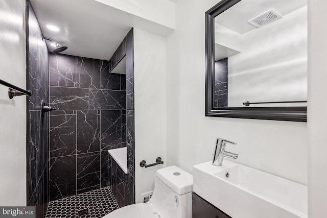 full bathroom featuring toilet, visible vents, a tile shower, and a sink