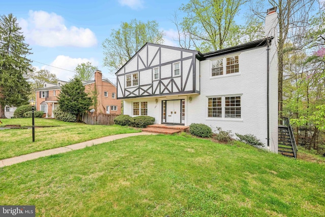 tudor house with brick siding, fence, a chimney, and a front yard