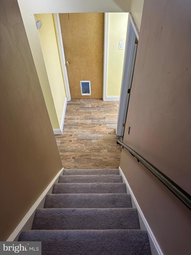 staircase with baseboards and wood finished floors