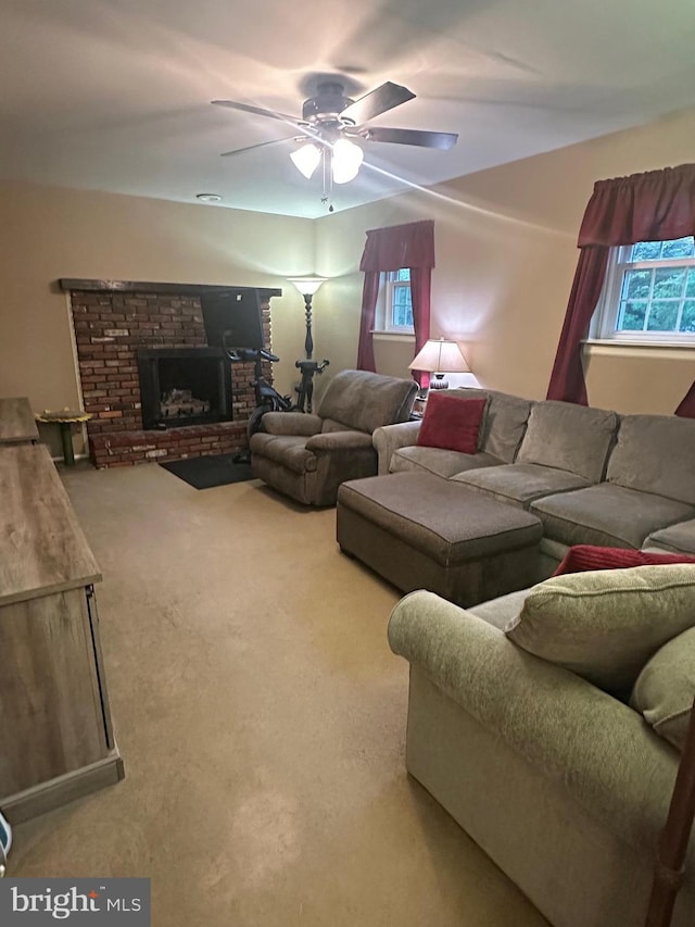 living area featuring carpet floors, a ceiling fan, a brick fireplace, and a wealth of natural light