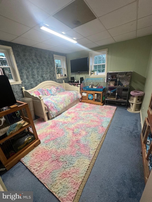 carpeted bedroom featuring wallpapered walls, multiple windows, and a paneled ceiling