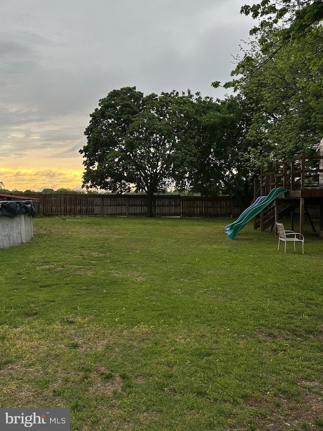 yard at dusk with a playground and fence