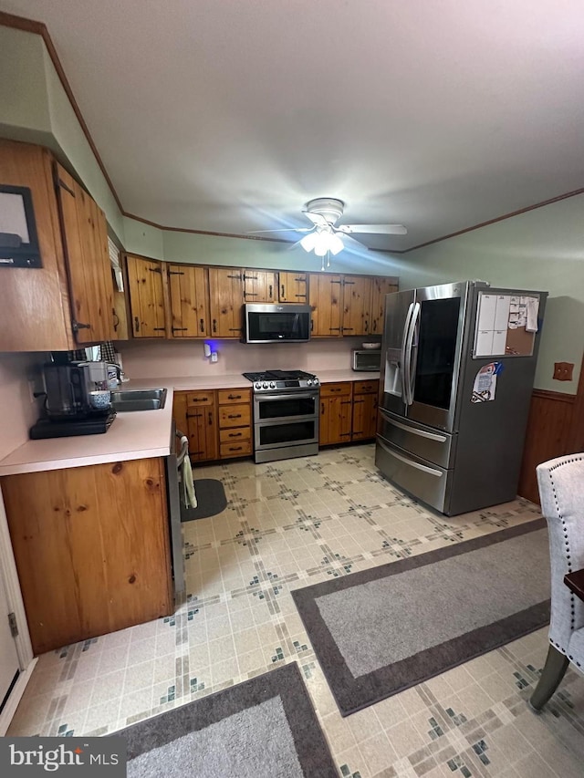 kitchen featuring brown cabinetry, light countertops, ceiling fan, and stainless steel appliances