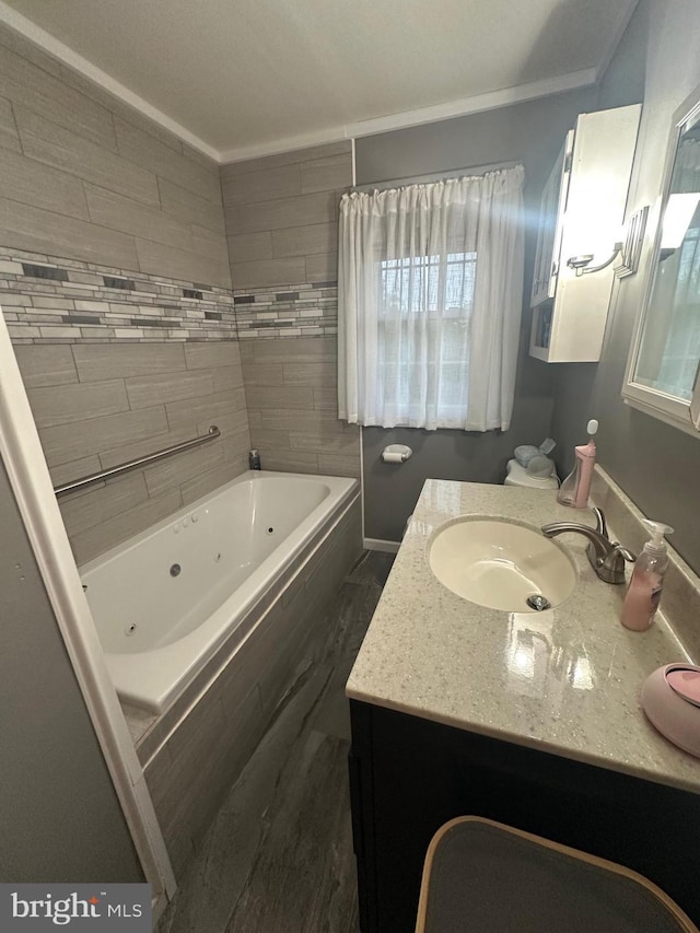 bathroom featuring a tub with jets, baseboards, and vanity