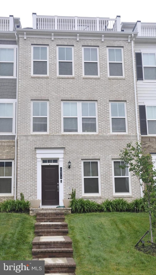 multi unit property featuring brick siding and a front yard