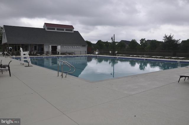 pool with a patio area and fence