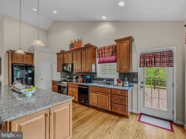 kitchen featuring black appliances, high vaulted ceiling, light wood-style floors, a sink, and plenty of natural light