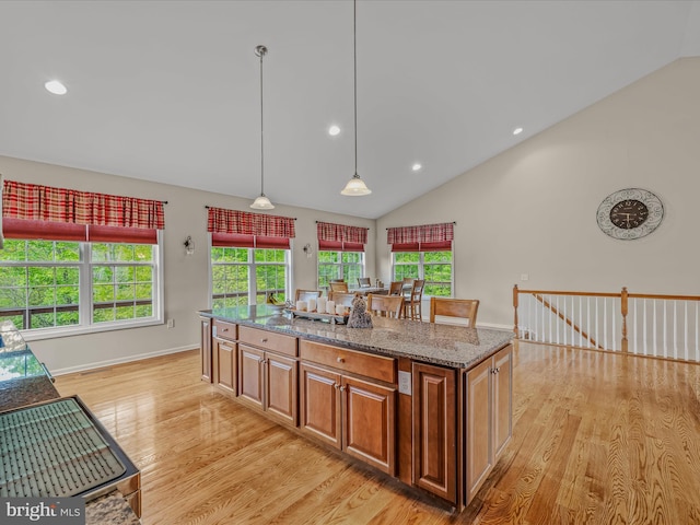 kitchen featuring vaulted ceiling, light wood-style floors, stone countertops, pendant lighting, and recessed lighting